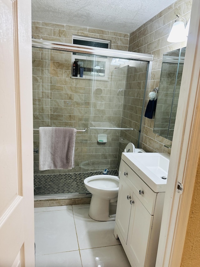 bathroom featuring vanity, tile patterned flooring, toilet, a textured ceiling, and a shower with shower door