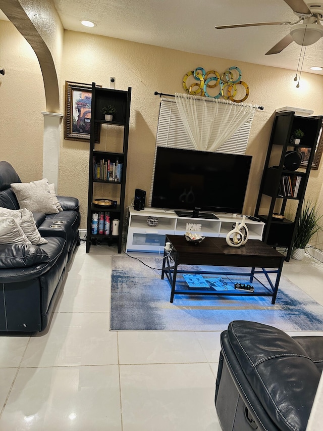 tiled living room with ceiling fan and a textured ceiling