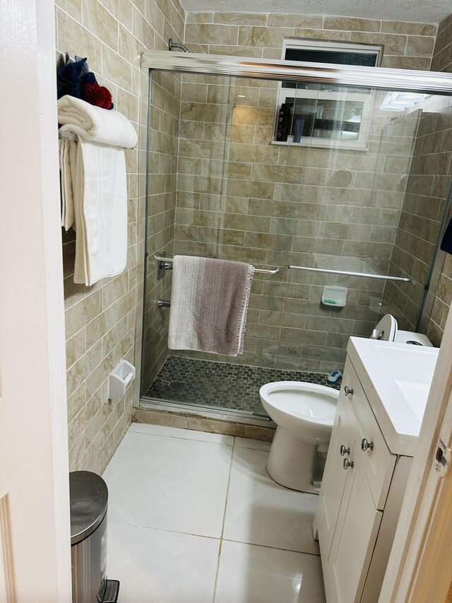 bathroom with tile patterned flooring, vanity, toilet, and an enclosed shower