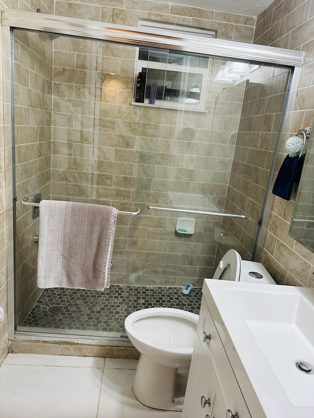 bathroom featuring tile patterned flooring, vanity, toilet, and a shower with door