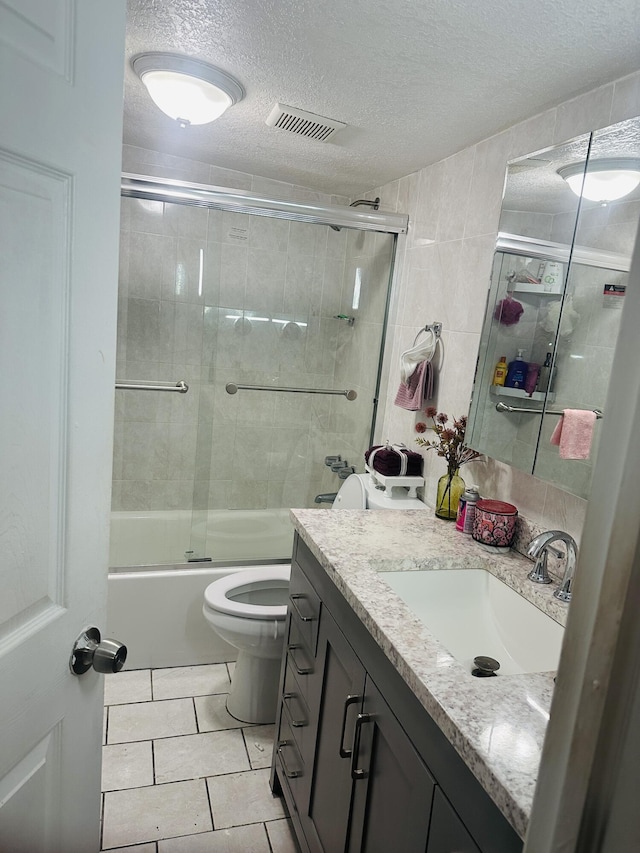 full bathroom featuring vanity, tile patterned floors, bath / shower combo with glass door, toilet, and a textured ceiling