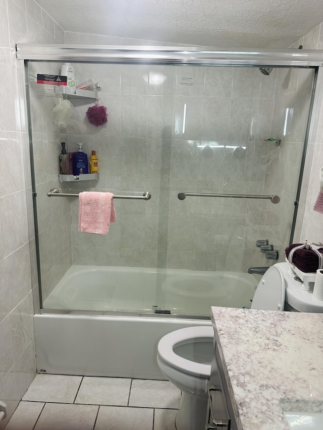 full bathroom with bath / shower combo with glass door, a textured ceiling, vanity, tile patterned flooring, and toilet