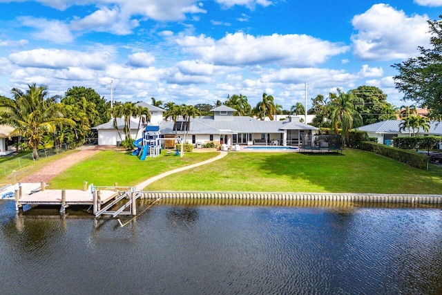 back of house featuring a water view, a yard, and a playground