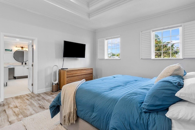 bedroom featuring ensuite bathroom, a tray ceiling, crown molding, and light hardwood / wood-style flooring