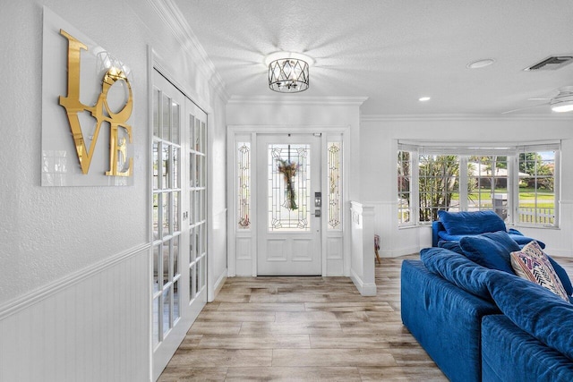 entryway with light hardwood / wood-style flooring, crown molding, and french doors