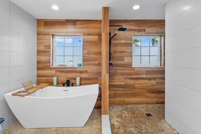 bathroom with plus walk in shower, a textured ceiling, and plenty of natural light