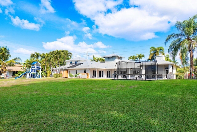 back of property featuring a playground, a trampoline, and a lawn