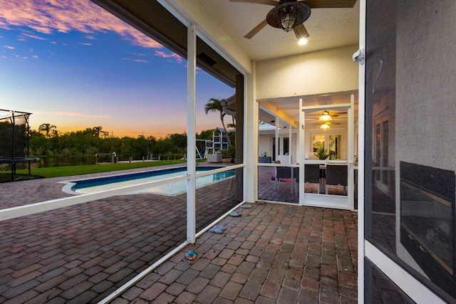 unfurnished sunroom with ceiling fan and a swimming pool