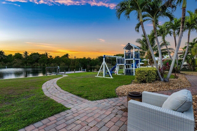 exterior space with a playground, a yard, and a water view