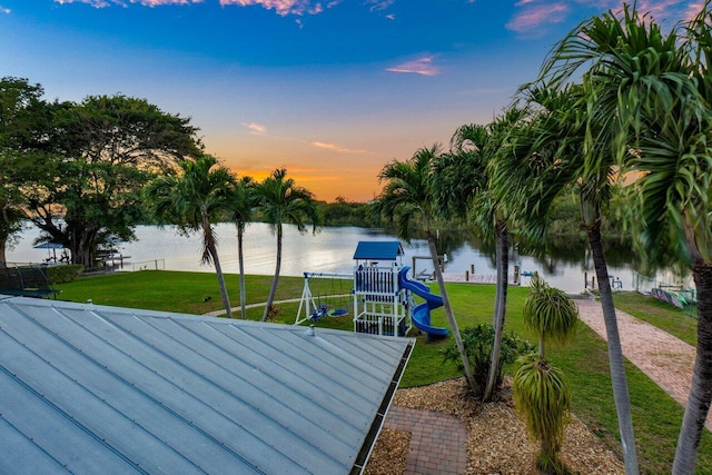 exterior space featuring a playground, a water view, and a yard