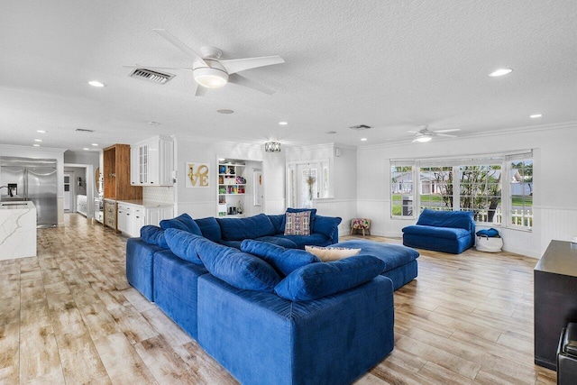 living room with ceiling fan, light wood-type flooring, and ornamental molding