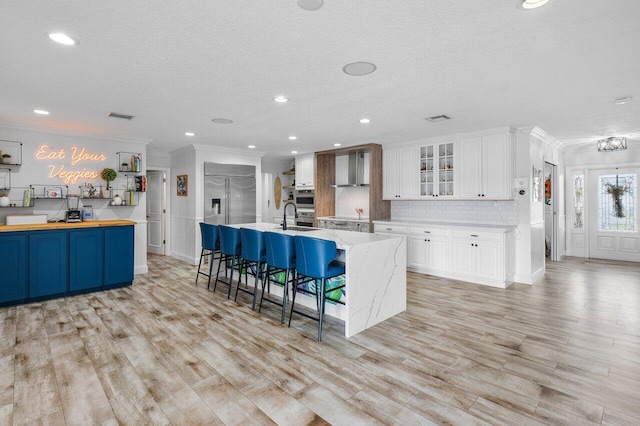 kitchen with white cabinets, a kitchen island with sink, a breakfast bar, and sink