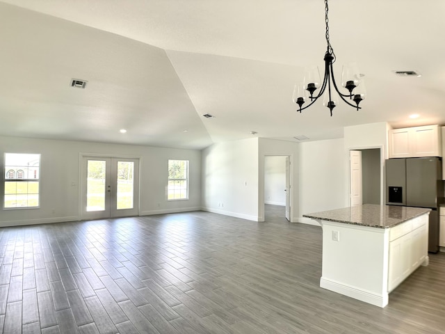 kitchen featuring stainless steel fridge, dark stone counters, an inviting chandelier, white cabinets, and a center island