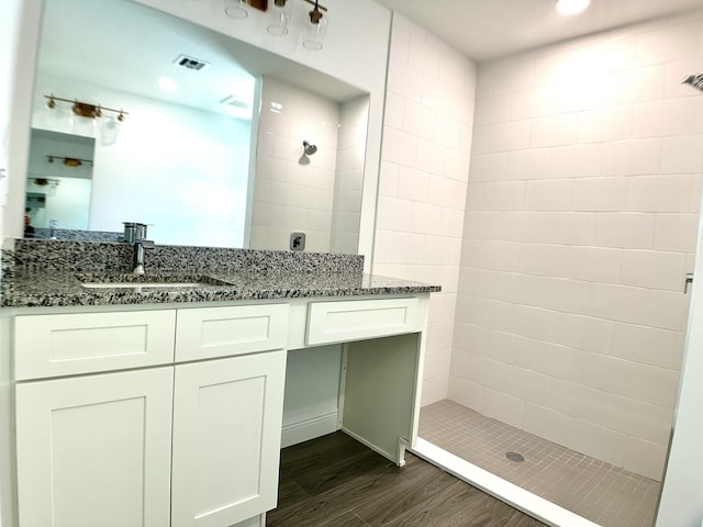 bathroom featuring a tile shower, vanity, and hardwood / wood-style flooring