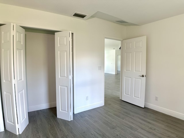 unfurnished bedroom featuring dark hardwood / wood-style flooring and a closet