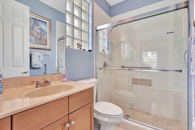 bathroom with vanity, toilet, and a shower with door