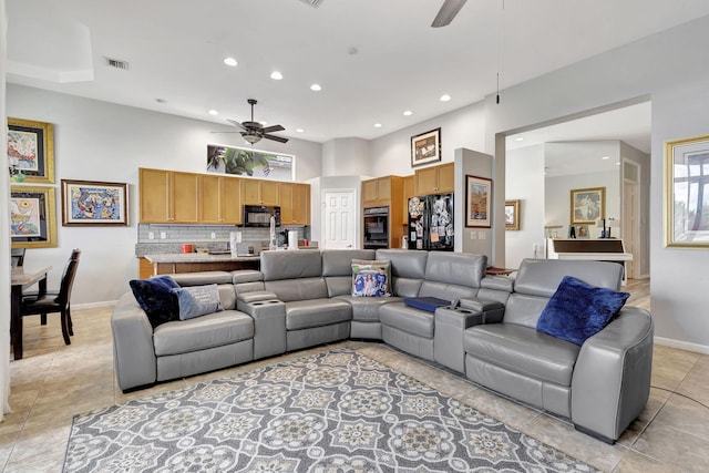 tiled living room with ceiling fan and a high ceiling