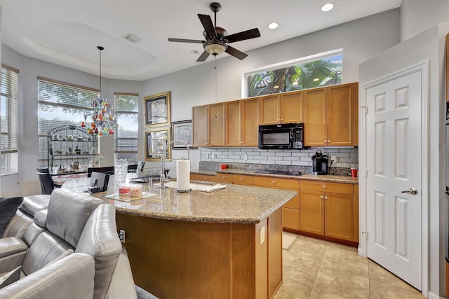 kitchen with light stone countertops, ceiling fan, hanging light fixtures, light tile patterned floors, and black appliances