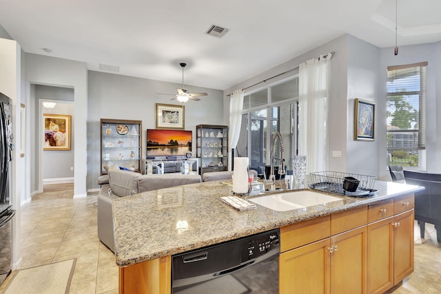 kitchen featuring light stone countertops, ceiling fan, sink, stainless steel dishwasher, and an island with sink