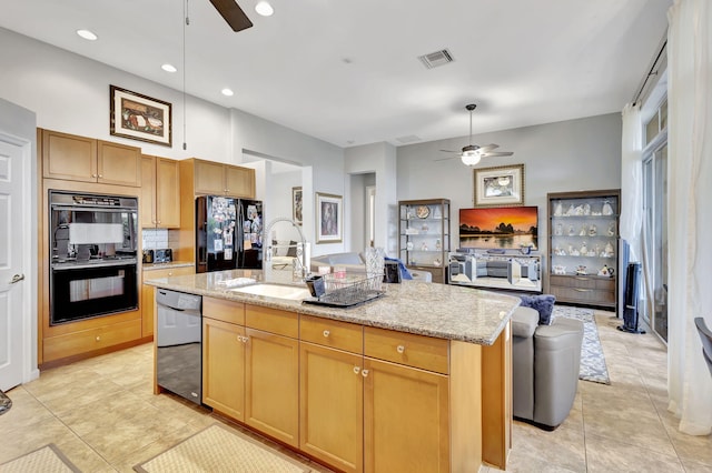 kitchen with black appliances, sink, light stone countertops, an island with sink, and light tile patterned floors