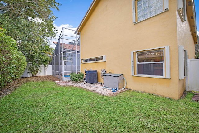 exterior space featuring a lawn and glass enclosure