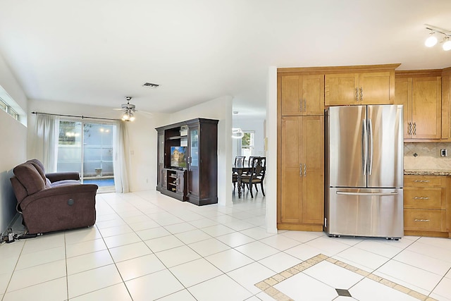 kitchen with light stone countertops, stainless steel fridge, tasteful backsplash, ceiling fan, and light tile patterned flooring