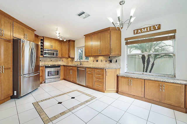 kitchen featuring stainless steel appliances, light stone counters, tasteful backsplash, and a notable chandelier