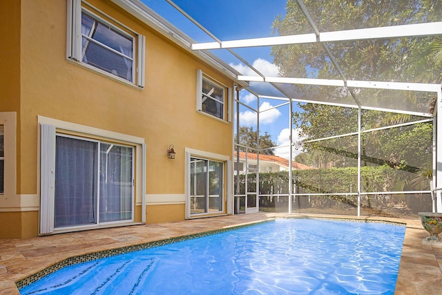 view of pool with glass enclosure and a patio