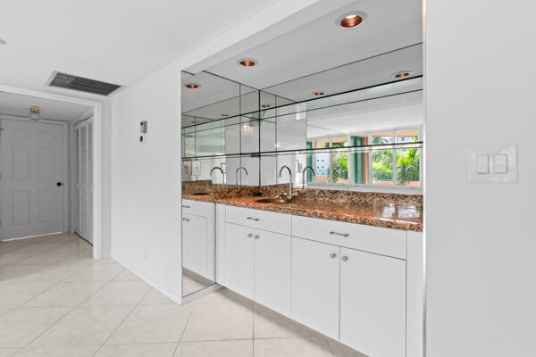 bar featuring light tile patterned floors, sink, dark stone counters, and white cabinets