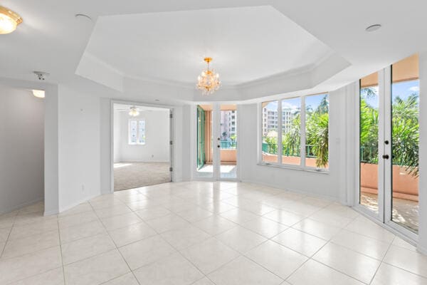 spare room with a raised ceiling, light tile patterned floors, and french doors
