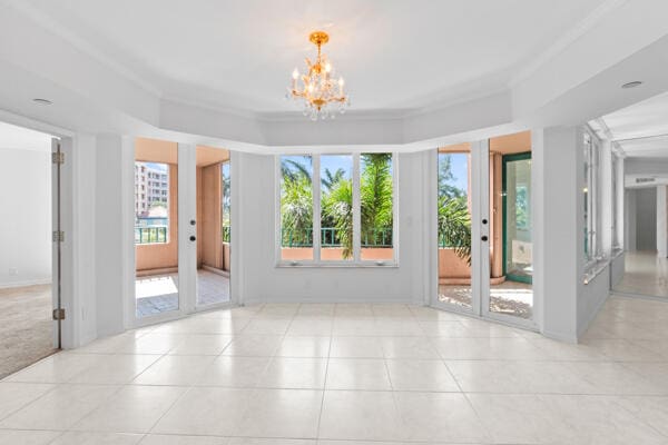 spare room featuring light tile patterned floors, ornamental molding, and a chandelier