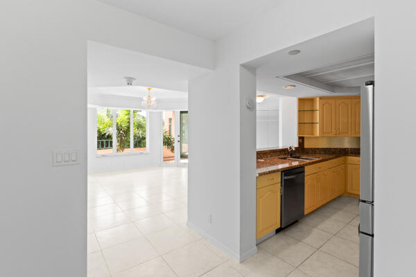 kitchen with black dishwasher, sink, stainless steel fridge, and light brown cabinetry