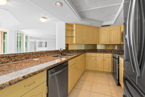 kitchen featuring sink, light tile patterned floors, a tray ceiling, stainless steel appliances, and light brown cabinets