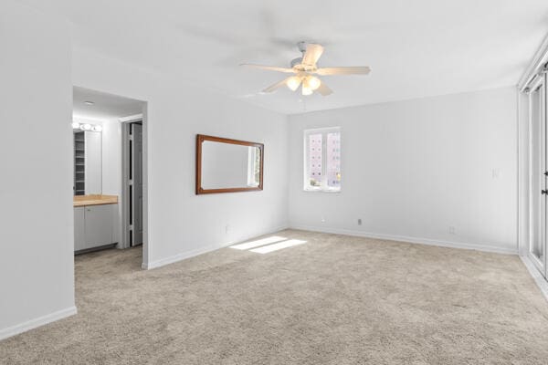 unfurnished bedroom with ceiling fan, light colored carpet, and ensuite bathroom