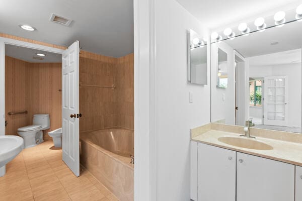bathroom featuring a tub, tile patterned flooring, vanity, toilet, and a bidet