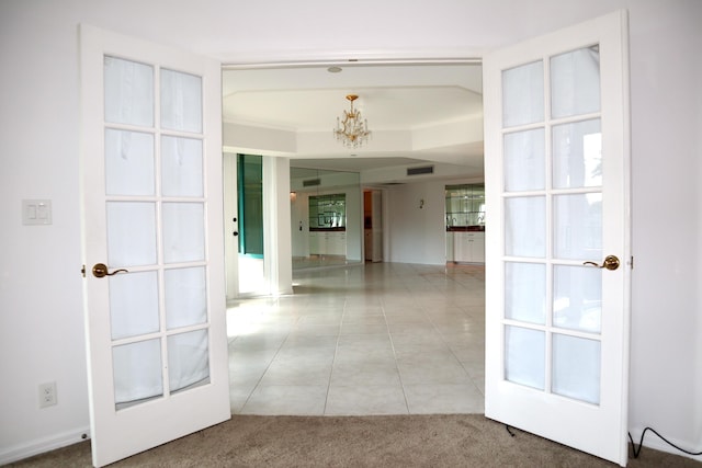 hallway featuring light colored carpet, french doors, and a chandelier