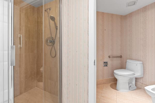 bathroom with a bidet, tile patterned floors, toilet, and a shower with shower door