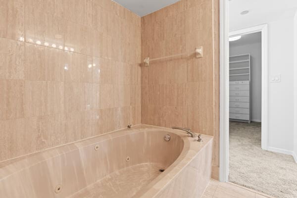 bathroom featuring a relaxing tiled tub, tile patterned flooring, and tile walls