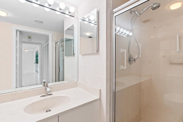 bathroom featuring a shower with door and vanity