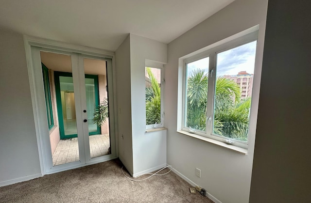 entryway with carpet flooring, a wealth of natural light, and french doors