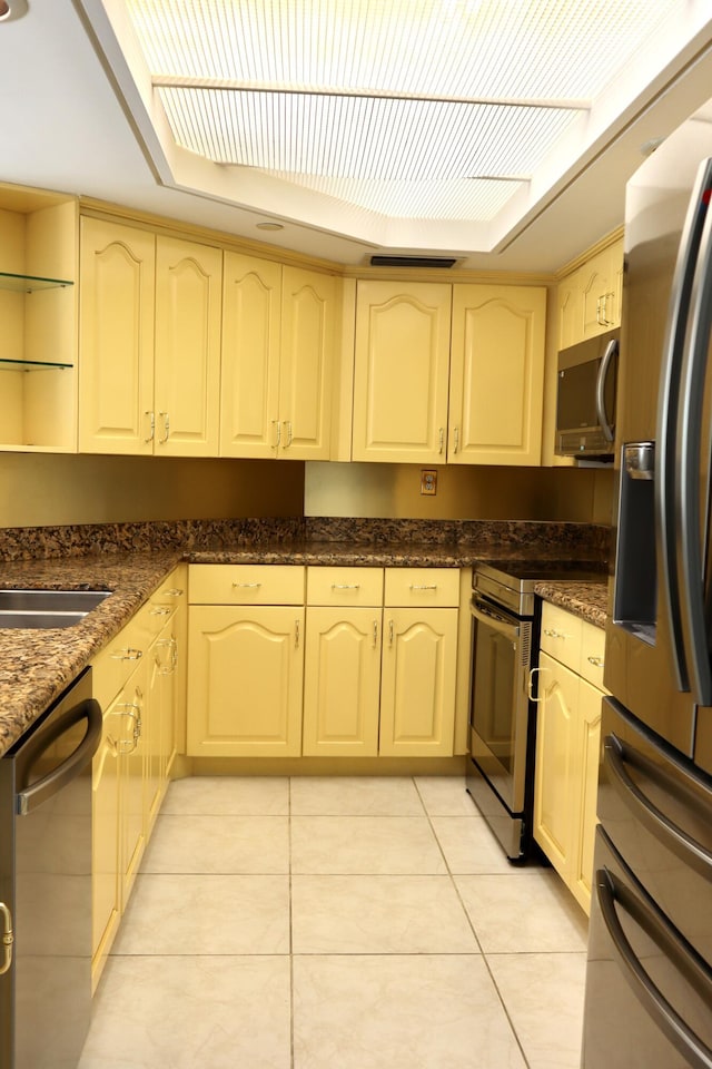 kitchen with light tile patterned floors, appliances with stainless steel finishes, and dark stone counters