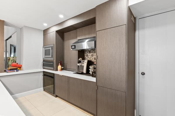 kitchen with stainless steel microwave, oven, and light tile patterned floors