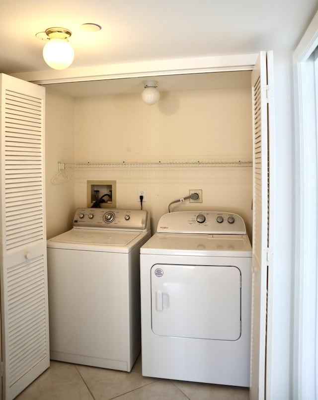 clothes washing area featuring washer and clothes dryer and light tile patterned flooring