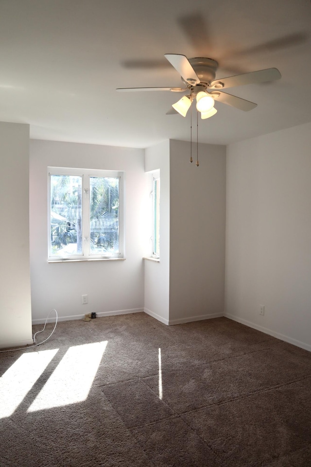 spare room featuring ceiling fan and dark colored carpet