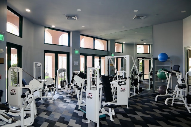 exercise room featuring dark colored carpet and a towering ceiling