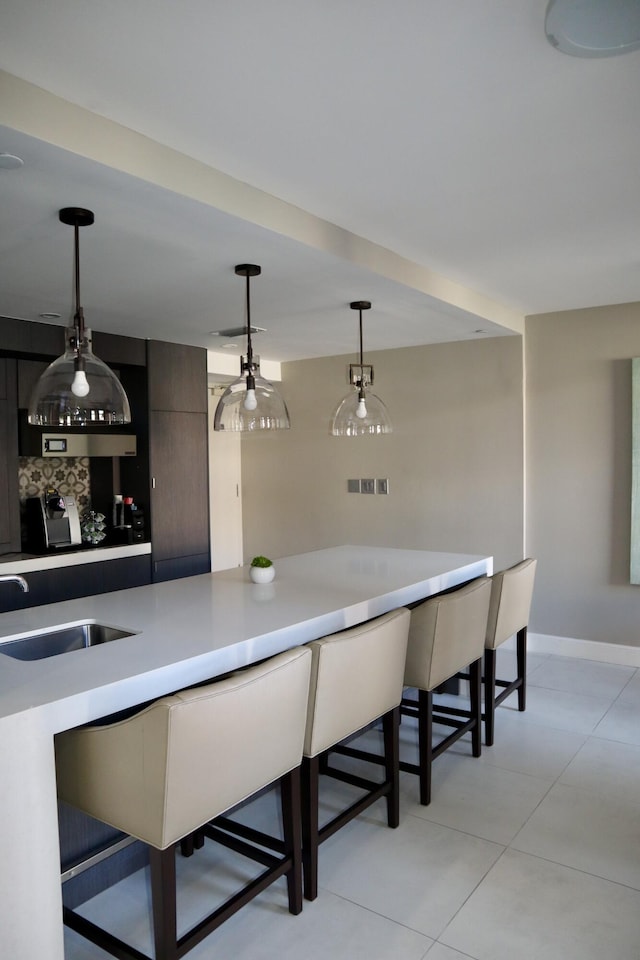 bar featuring sink, light tile patterned floors, and decorative light fixtures