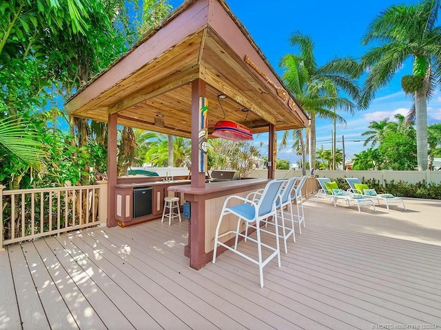 wooden deck featuring exterior bar and area for grilling