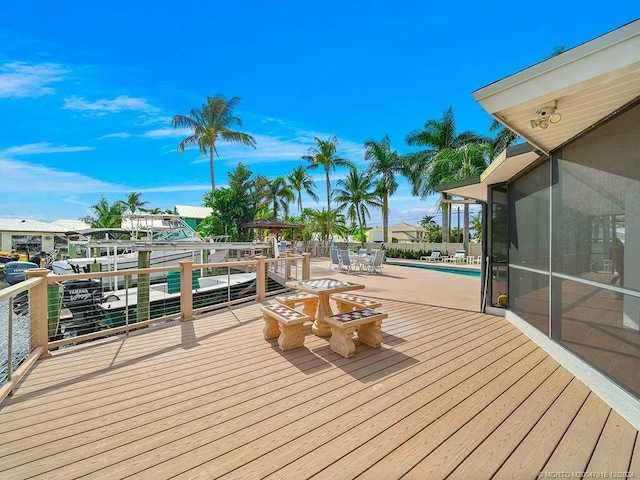 wooden deck with a dock and a pool