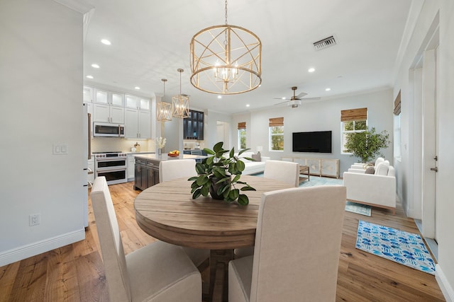 dining space with light hardwood / wood-style floors, ceiling fan with notable chandelier, and ornamental molding