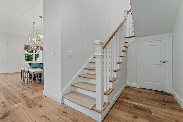 staircase featuring hardwood / wood-style floors and a notable chandelier